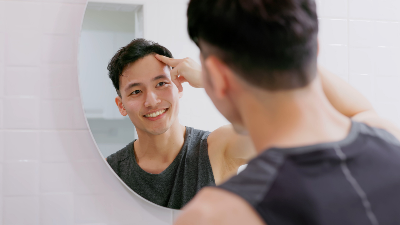 生え際を抑えている男性